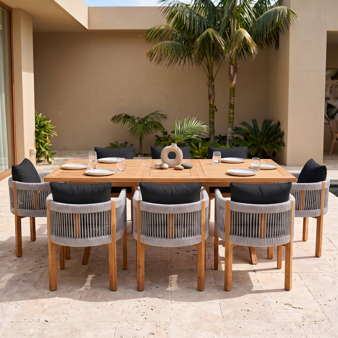 Outdoor wooden dining set with chairs on a patio with tropical greenery