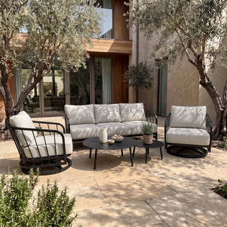 Modern outdoor patio furniture set arranged on a stone patio in a real outdoor setting