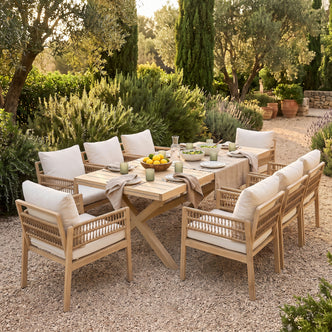 Outdoor wooden dining set styled on a pebble patio with greenery