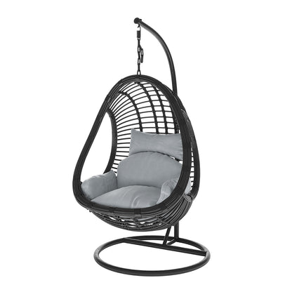 Deanna Curved Rattan Hanging Outdoor Egg Chair in Black features a freestanding, egg-shaped wicker shell, suspended from a curved metal frame with plush gray cushions for comfort.