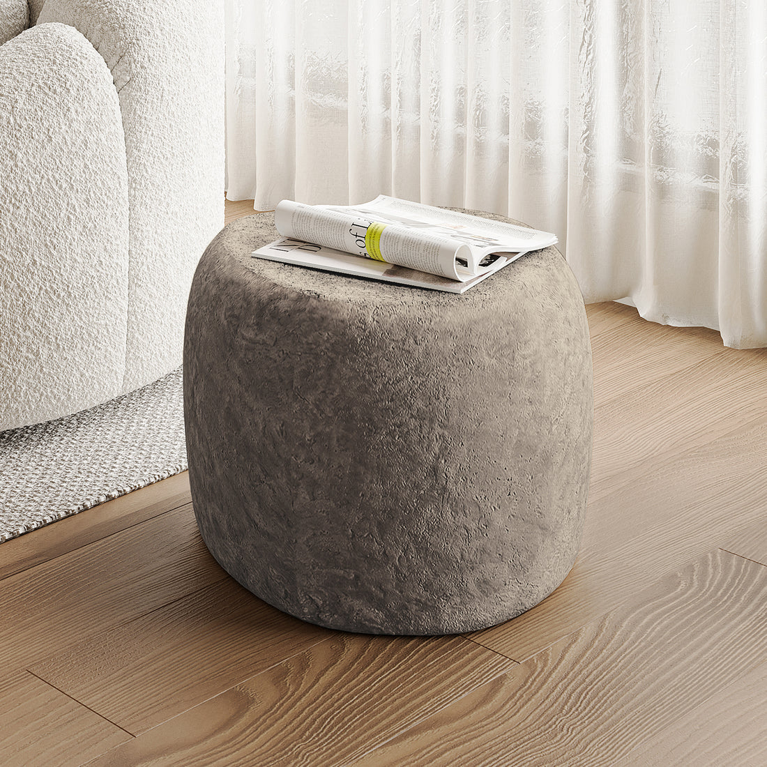 Close-up of the Hollie Indoor/Outdoor Round Concrete Side Table with a magazine on top, showcasing its sturdy, natural concrete design and versatile use in modern farmhouse decor.