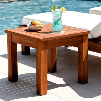 Laurette Outdoor Timber Side Table in Natural, placed poolside, holds a white bowl of fruit and a glass of blue drink, embodying summer relaxation with its durable, FSC Eucalyptus design.