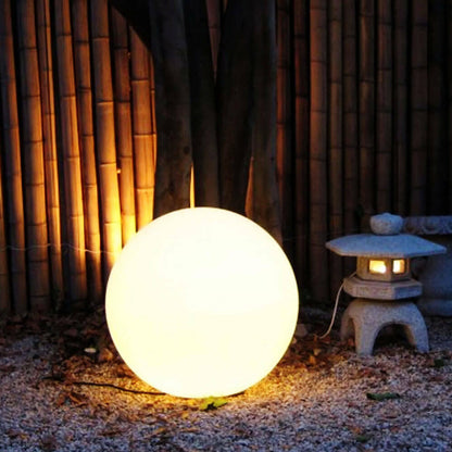Waterproof Outdoor LED Ball Lights Décor 40cm, featuring a sleek, round design, illuminated and positioned in front of a bamboo wall, perfect for enhancing outdoor settings with versatile, enchanting lighting.