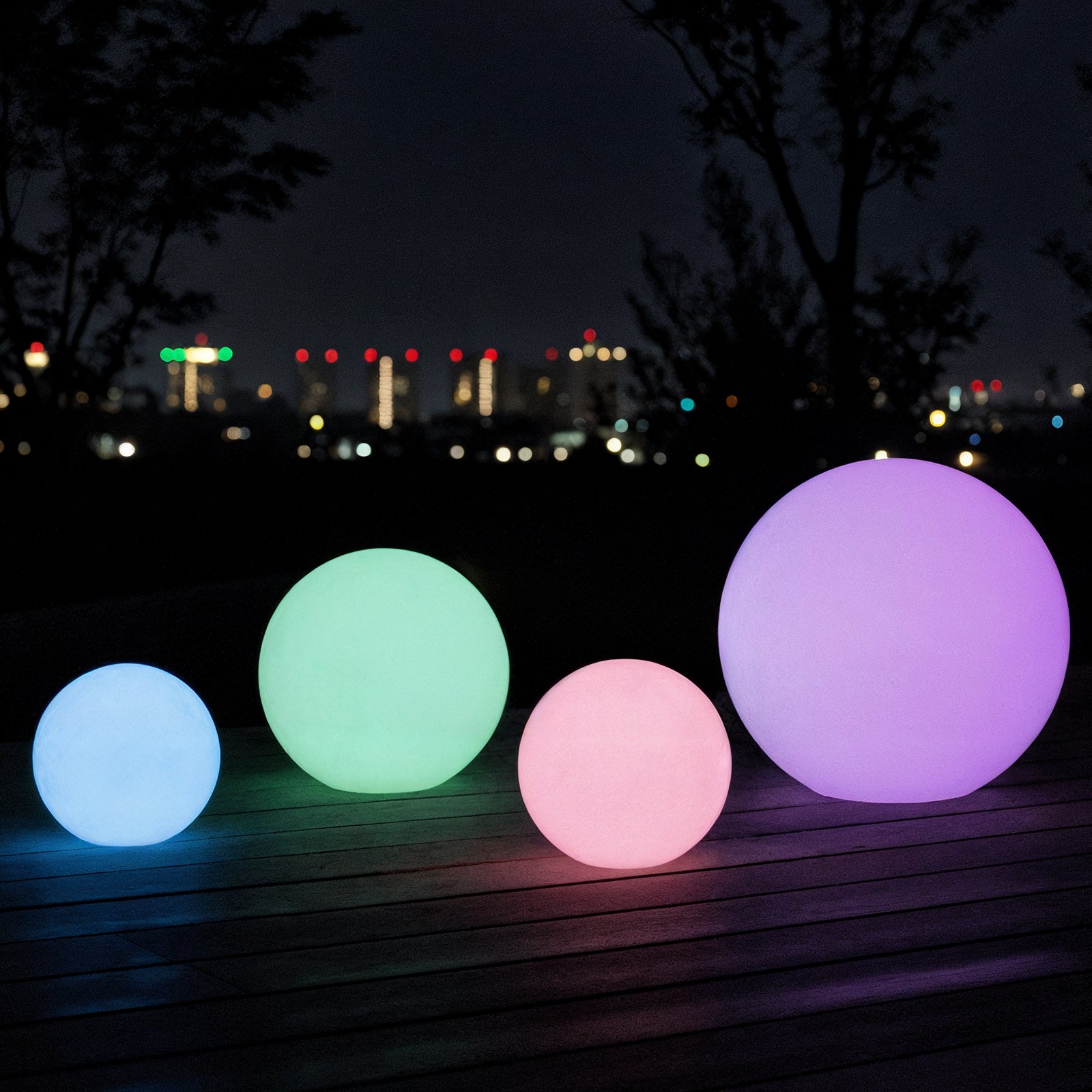 Sphero 50cm Floating Waterproof Outdoor LED Ball Lights displayed in varying sizes, glowing softly on a wooden patio at night, creating an enchanting atmosphere with its spherical design.