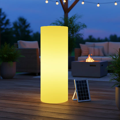 70cm Outdoor Solar LED Bollard Light with Remote Control glows warmly on a wooden deck. A small solar panel sits beside it, with wicker chairs, a fire-pit table, and string lights behind.