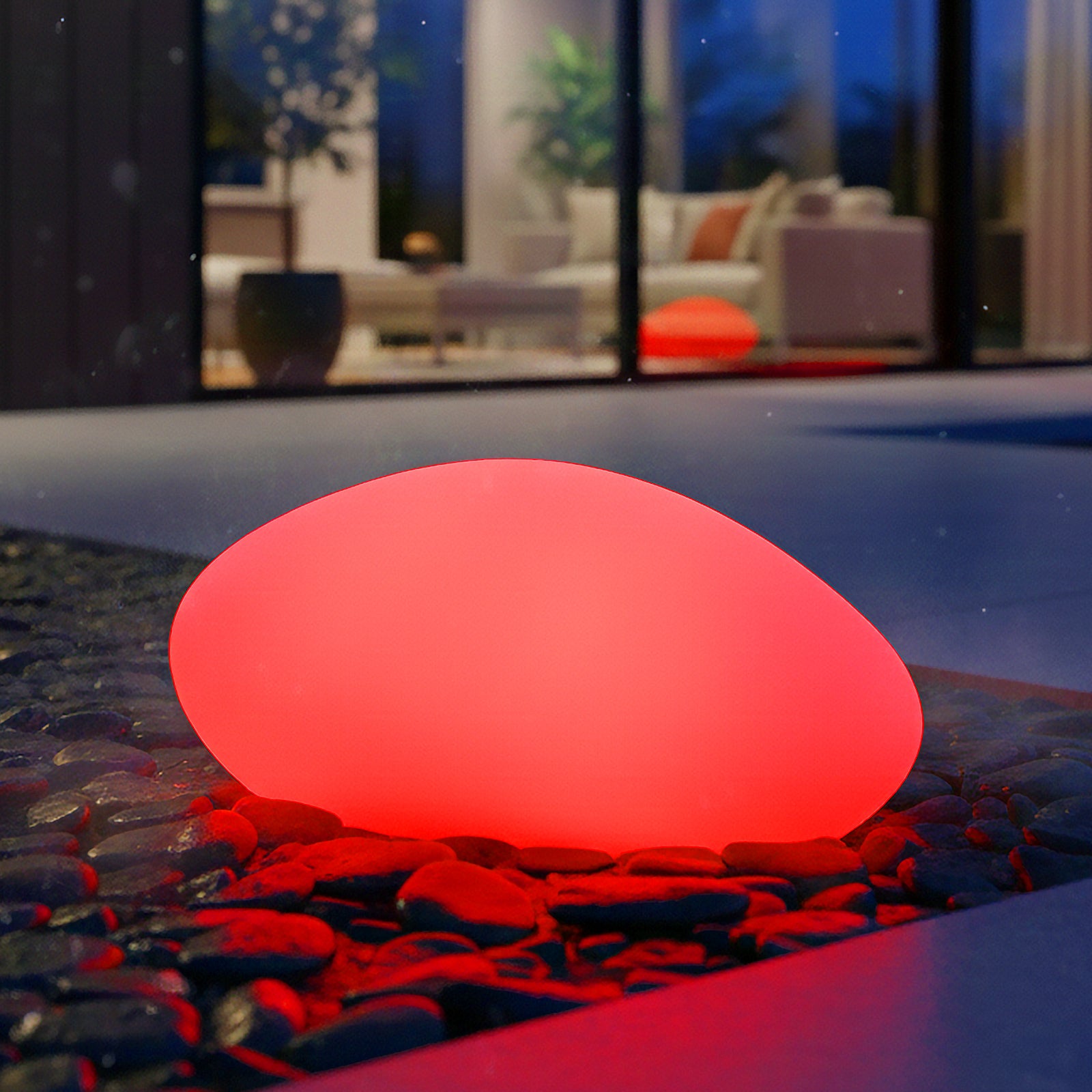 Smooth, pebble-shaped 32cm Waterproof Solar Charging Outdoor LED Rock Light glows red among decorative stones on a patio, enhancing outdoor ambiance with discreet design and versatile lighting options.