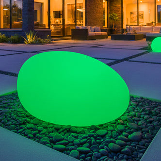 40cm Waterproof Solar Charging Outdoor LED Rock Light nestled in river stones, glowing in a modern patio scene at night with a contemporary home backdrop, enhancing outdoor ambience effortlessly.