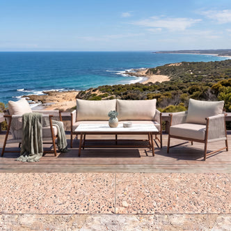 Outdoor patio furniture set arranged on a wooden deck overlooking the ocean