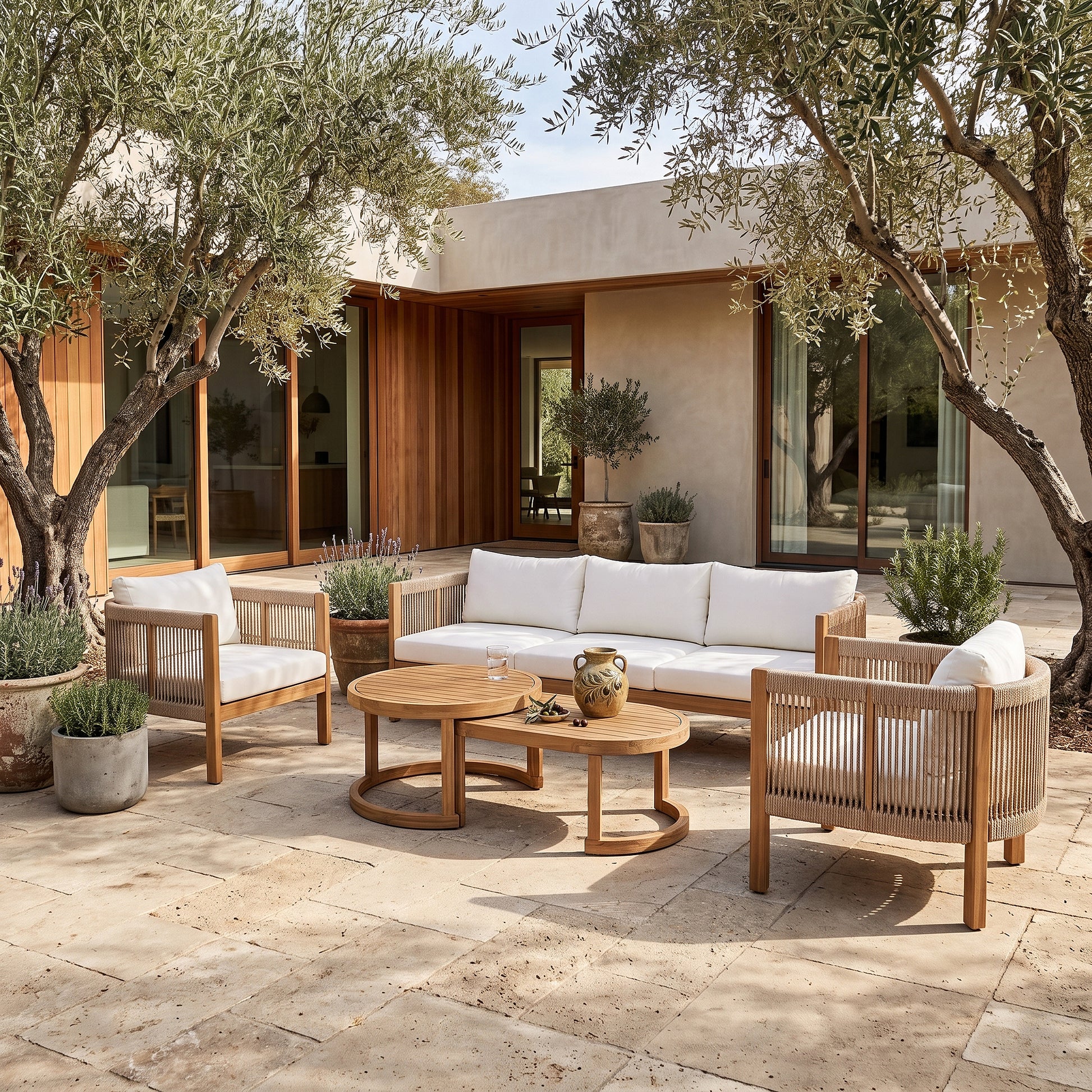 Outdoor furniture set arranged on a patio with plants and a modern house in the background