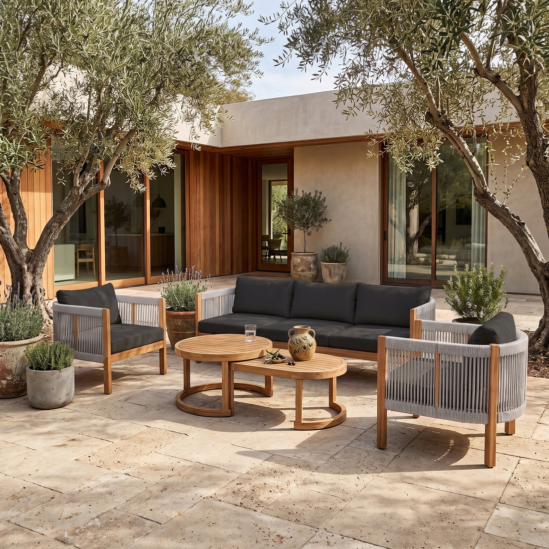 Outdoor patio furniture set arranged on a stone patio with plants and a house in the background