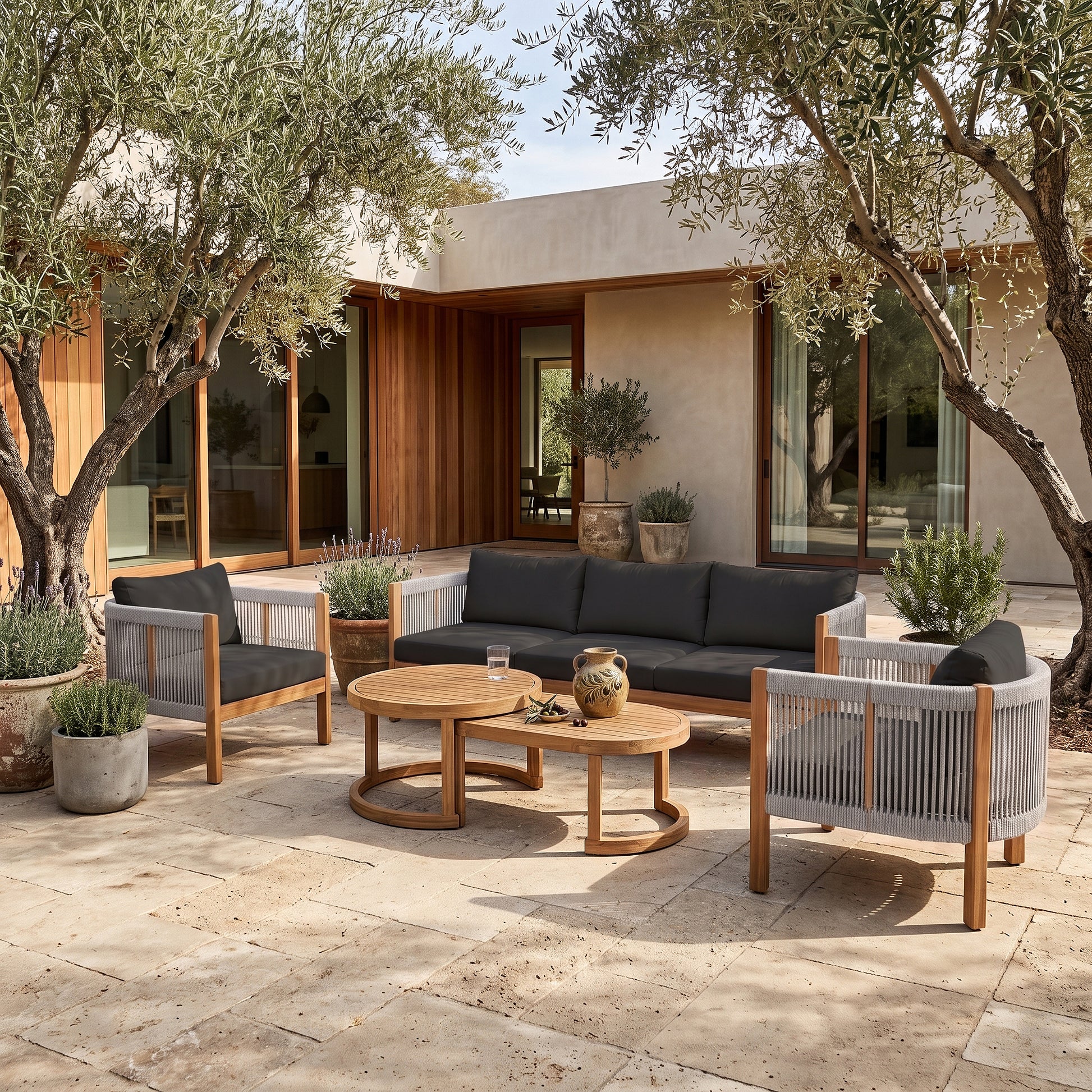 Outdoor patio furniture set arranged on a stone patio with plants and a house in the background
