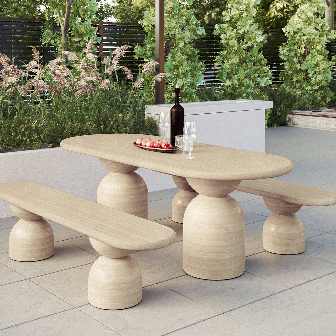 Lumen Indoor/Outdoor Concrete Dining Table Set with Bench Beige displayed outdoors with a bowl of pomegranates, highlighting its elegant oval shape and sturdy cone-shaped base on a coffee table.
