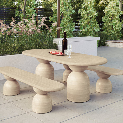 Lumen Indoor/Outdoor Concrete Dining Table Set with Bench Beige displayed outdoors with a bowl of pomegranates, highlighting its elegant oval shape and sturdy cone-shaped base on a coffee table.