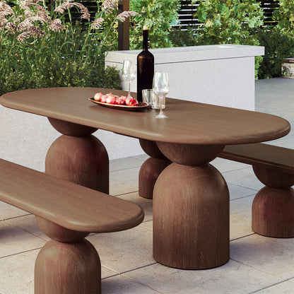 Lumen 220cm Oval Indoor/Outdoor Concrete Dining Table Chestnut features an elegant oval shape with a cone-shaped base, set on a coffee table alongside pomegranates and a wine glass.