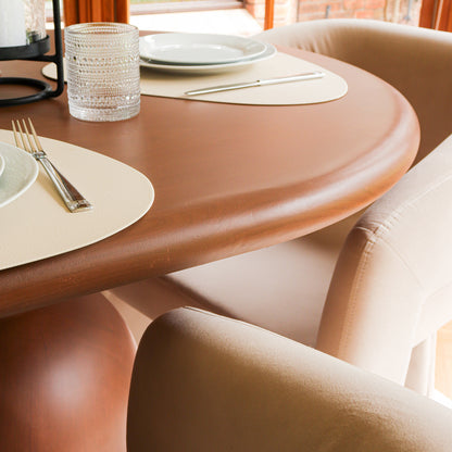 Lumen 220cm Oval Outdoor Concrete Dining Table in Chestnut, showcasing an elegant oval top and unique cone-shaped base, surrounded by upholstered beige chairs and set with plates and glasses.