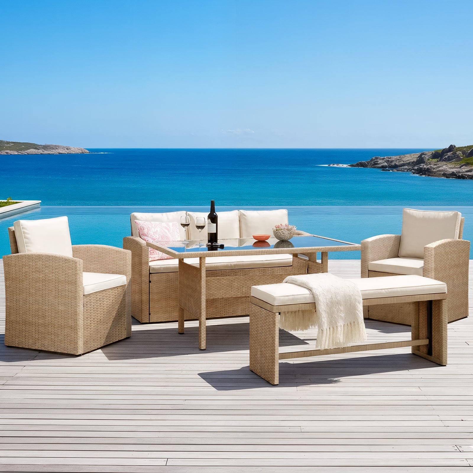 Mapa 7 Seater Wicker Outdoor Dining Sofa Set in Natural on a deck with armchairs, loveseat, cushioned bench, and glass-topped table beside an infinity pool overlooking a turquoise ocean bay.