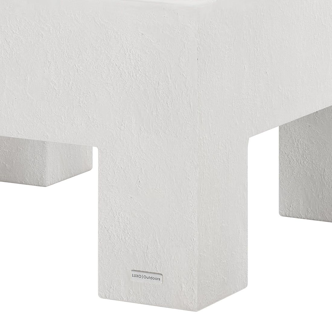 Detail shot of the Maxon White concrete coffee table's surface and leg, featuring the Luxo Outdoors tag
