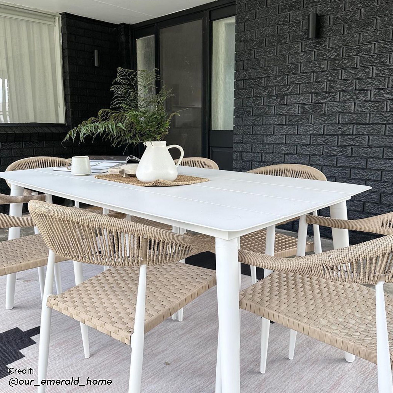 Nemma 6-Seater Aluminium Outdoor Dining Set features a sleek table with wicker chairs and a white vase, perfect for patio or garden gatherings.