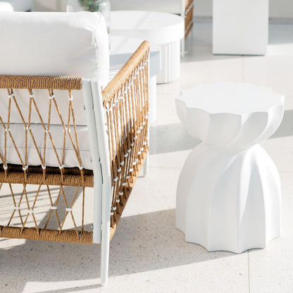 Nuevo 4 Seater Wicker Outdoor Lounge Set in Light Beige, featuring a white metal frame, plush white cushions, and a sculptural side table, set on a polished concrete floor.