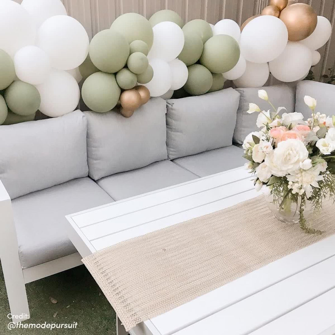 Portland Outdoor Corner Sofa Lounge with Footstools on a studio couch, accented by balloons and a floral vase, highlighting its modern design and durable construction for stylish outdoor seating.