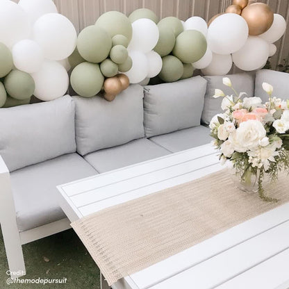 Portland Outdoor Corner Sofa Lounge with Footstools on a studio couch, accented by balloons and a floral vase, highlighting its modern design and durable construction for stylish outdoor seating.