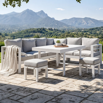 Portland Outdoor Corner Sofa Lounge with Footstools in White & Grey, featuring an L-shaped sectional, two ottomans, and a table with a succulent, set against scenic rolling hills and mountains.