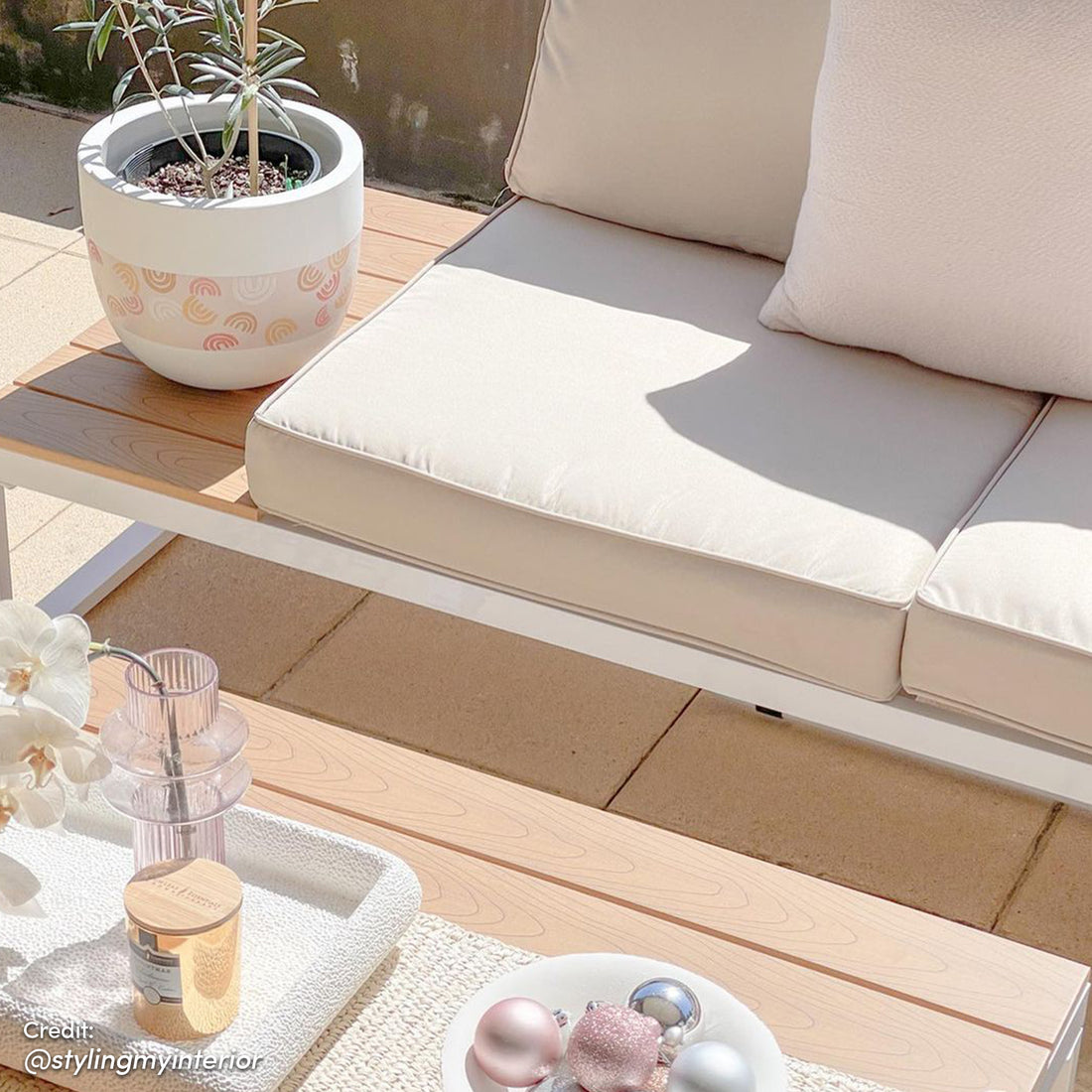 Rosa 5 Seater Outdoor Corner Sofa Lounge with Coffee Table shown in an outdoor setting, surrounded by a plant in a pot and ornaments on a table, highlighting its stylish design and comfortable seating.