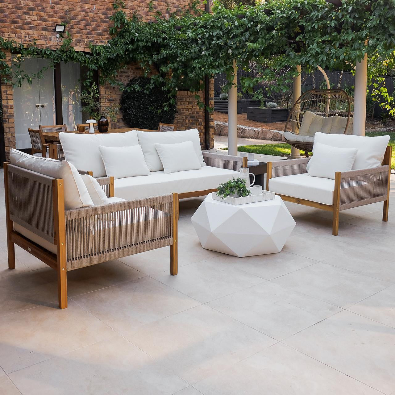 Savin 4-Seater Hardwood Outdoor Sofa Set in Beige features light wood frames, woven-rope sides, and plush off-white cushions, surrounding a white coffee table with a potted plant, enhancing outdoor elegance.