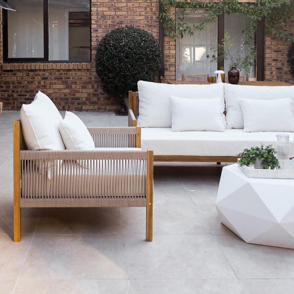 Savin 4-Seater Hardwood Outdoor Sofa Set in Beige on a tiled patio, featuring wooden frames, woven rope sides, and white cushions, complemented by a geometric coffee table with a plant and glass pitcher.