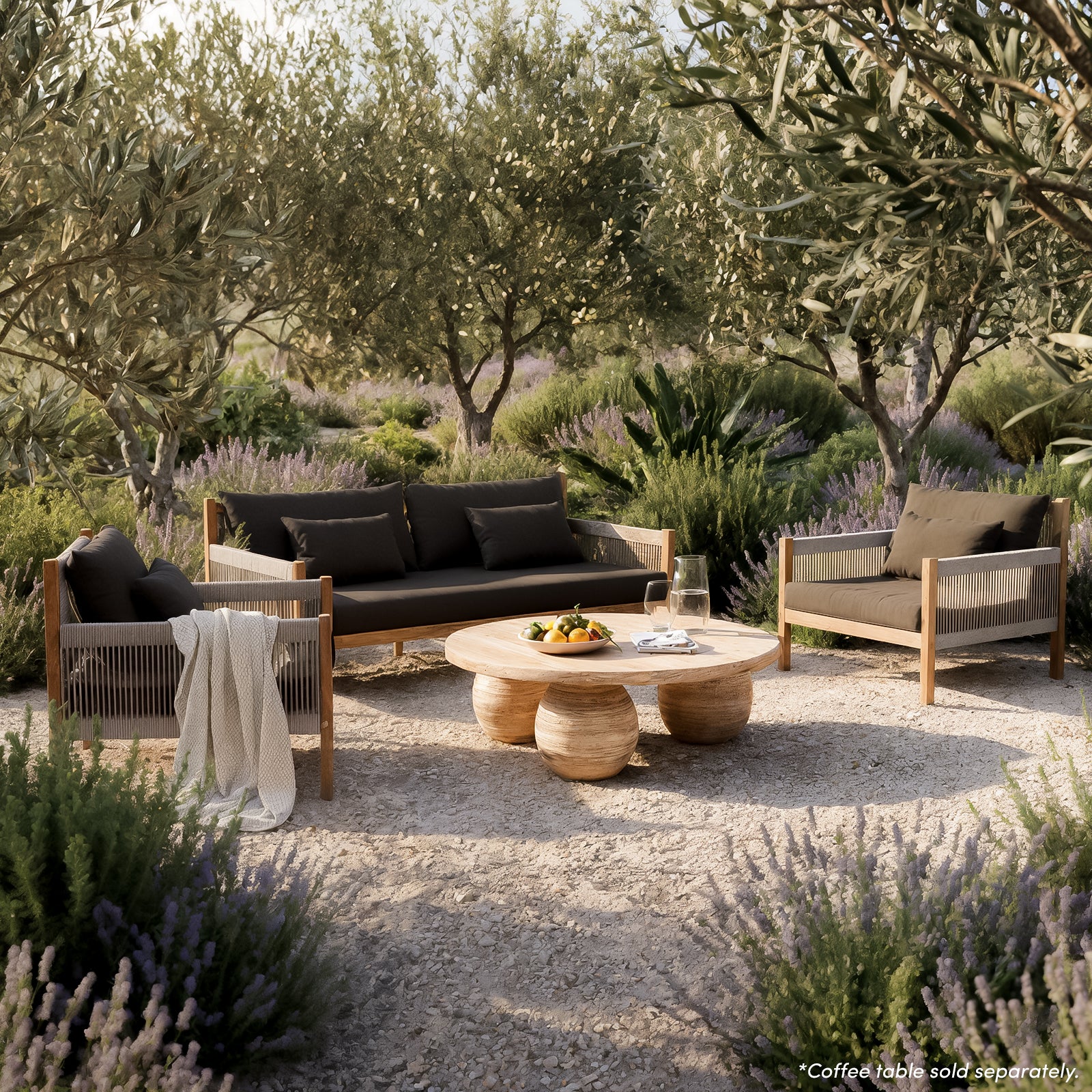 Savin 4 Seater Hardwood Outdoor Sofa Set in Light Grey on a stone terrace, featuring charcoal-cushioned sofa and armchairs with rope detailing, complemented by a wooden coffee table and coastal view.