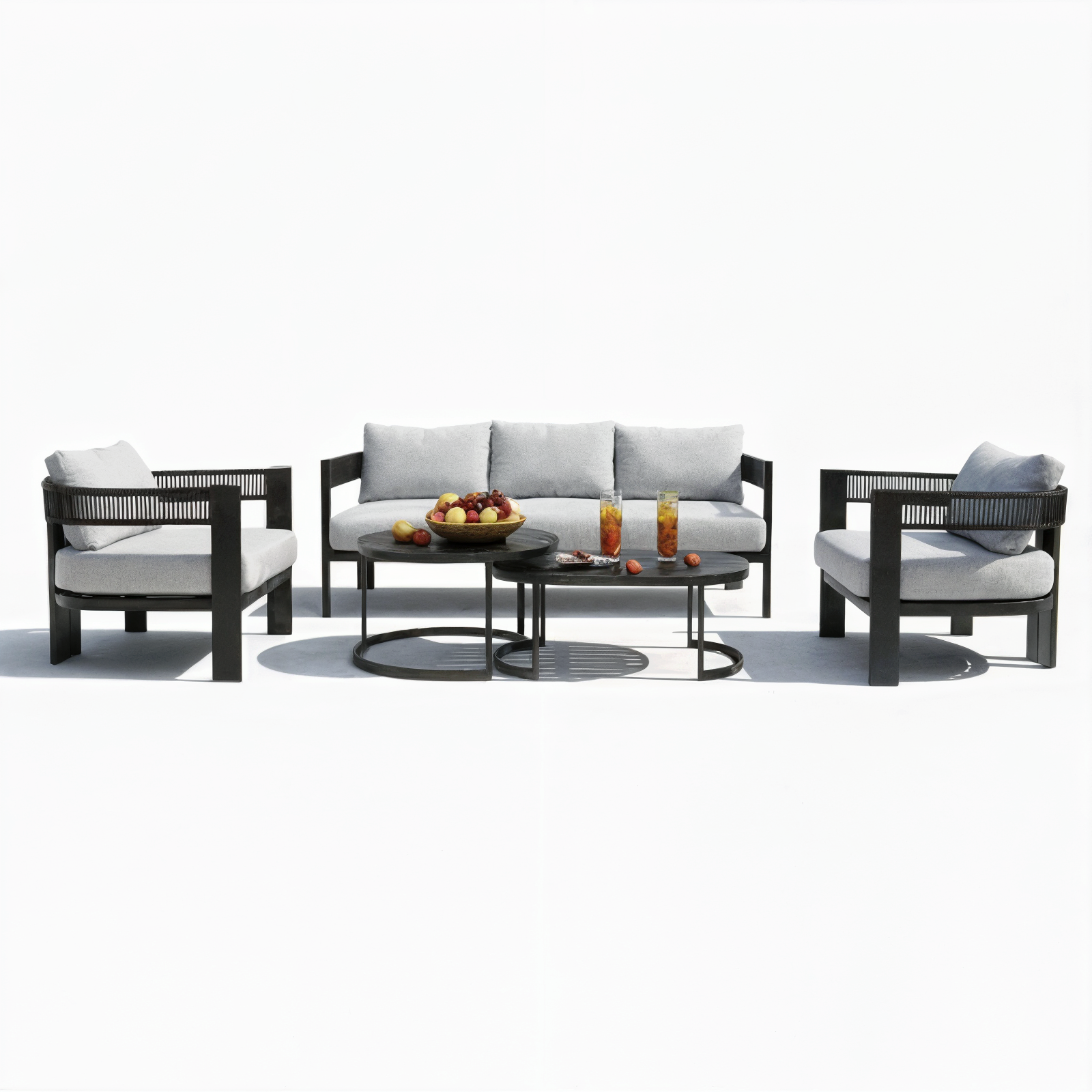 Sorrelle 5-Seater Curved Outdoor Sofa Set in Black, featuring light gray cushioned armchairs, a matching sofa, and two nesting coffee tables with fruit and drinks, arranged for a stylish patio setting.