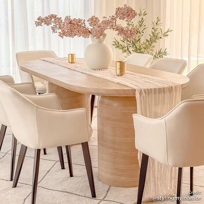 Tierre 200cm Concrete Indoor/Outdoor Dining Table in Beige, elegantly set with a blush runner and white vase, surrounded by cream armchairs, showcasing a modern, versatile aesthetic in a softly lit dining area.