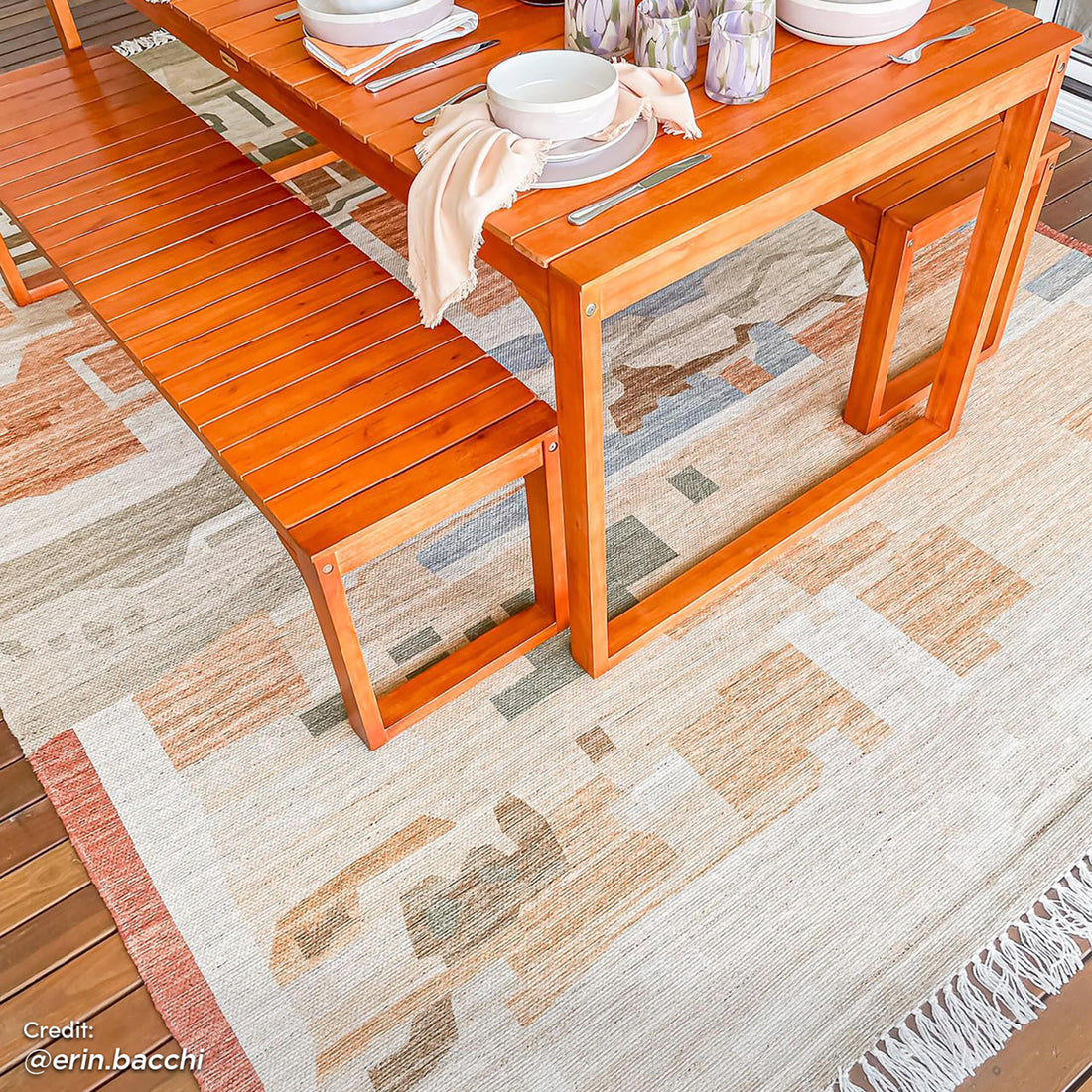 Trinity 8 Seater Hardwood Outdoor Dining Bench Set in Natural featuring an orange-stained table, matching benches on an earth-tone rug with dinnerware and candle holders, ideal for outdoor gatherings.