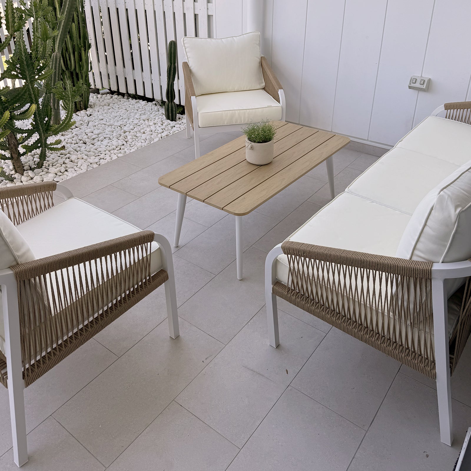 Vernon 5 Seater Aluminium Outdoor Sofa Set in Cream White featuring sleek white metal frames, woven rope sides, light-cream cushions, and a slatted wood-tone coffee table with a potted plant.