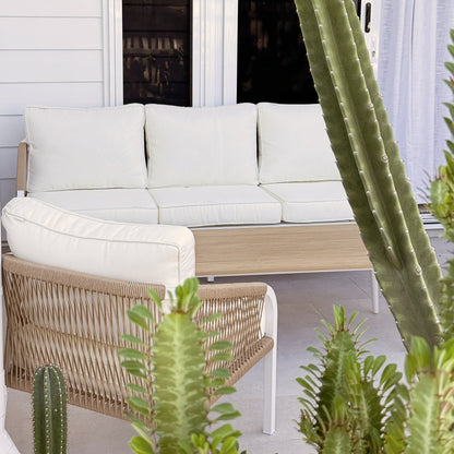 Vernon 5 Seater Aluminium Outdoor Sofa Set in Cream White, featuring a light-wood frame, white cushions, and woven rope armchair sides, nestled among tall succulents on a tiled patio.