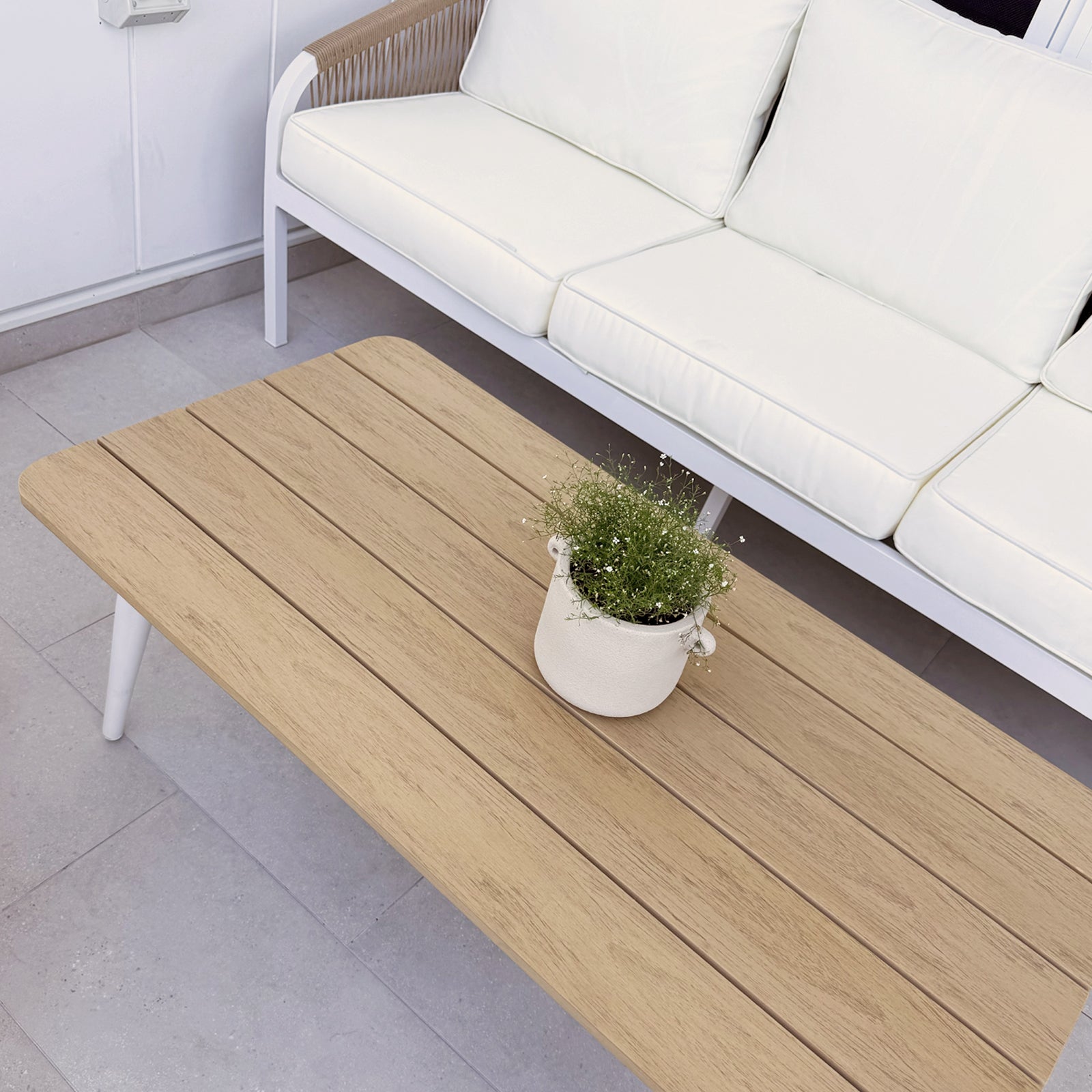 Vernon 5 Seater Aluminium Outdoor Sofa Set in Cream White featuring a low, wood-slatted coffee table with a ceramic pot and plant, complemented by a white-framed sofa with plush cushions.