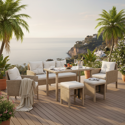 Sunny coastal terrace showcasing the Vero 7 Seater Wicker Outdoor Dining Sofa Set in Natural, with a rectangular table, cushioned bench, armchairs, stools, wine, and tropical plants against a serene sea backdrop.