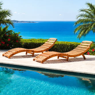 Wave Timber Outdoor Foldable Sun Lounge & Side Table Set featuring two curved wooden loungers alongside a pool, overlooking a bright blue sea, framed by palm fronds and red hibiscus blooms.
