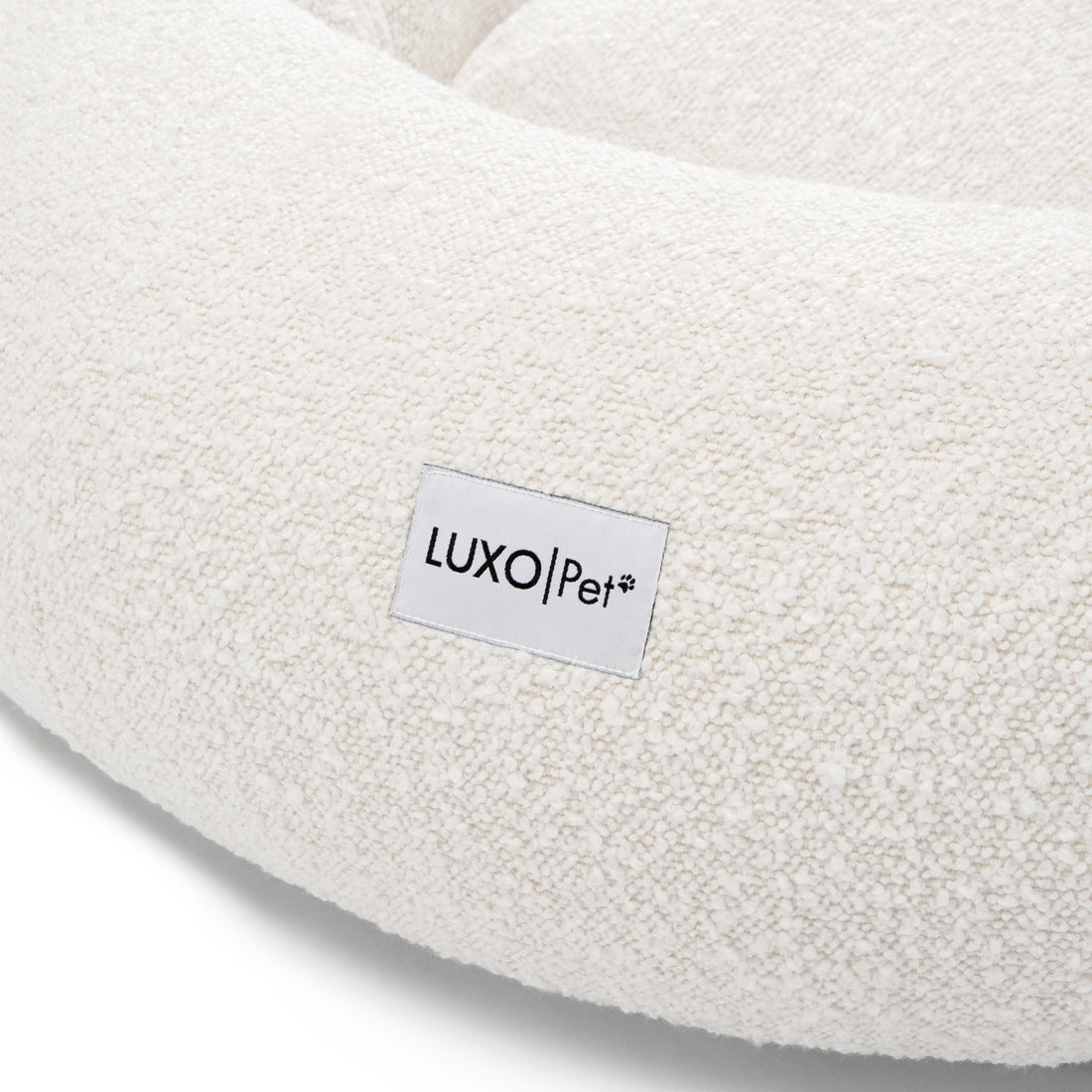 Kyra Large Boucle Pet Bed – Light Beige Plush Comfort featuring a close-up of white boucle fabric and a white label with black text, emphasizing its textured surface and premium design.