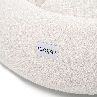 Kyra Large Boucle Pet Bed – Light Beige Plush Comfort featuring a close-up of white boucle fabric and a white label with black text, emphasizing its textured surface and premium design.