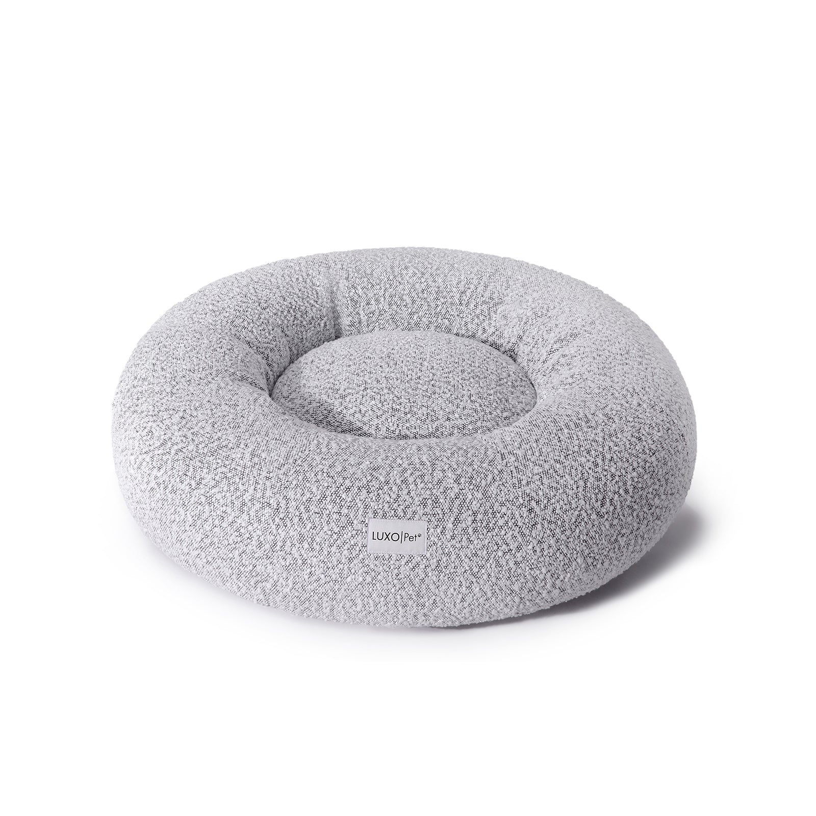 Kyra Medium Boucle Pet Bed – White with Black Base features a round, grey pillow design with soft curves and plush support, perfect for pets seeking comfort and modern style.