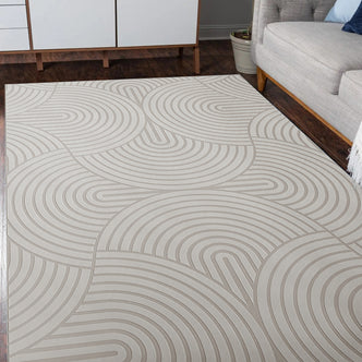 Alfy 120x180cm Small Tufted Modern Abstract Indoor Rug on dark hardwood floor, showcasing a concentric-arc pattern. Positioned between mid-century cabinet legs and a light-gray sofa with a potted plant nearby.