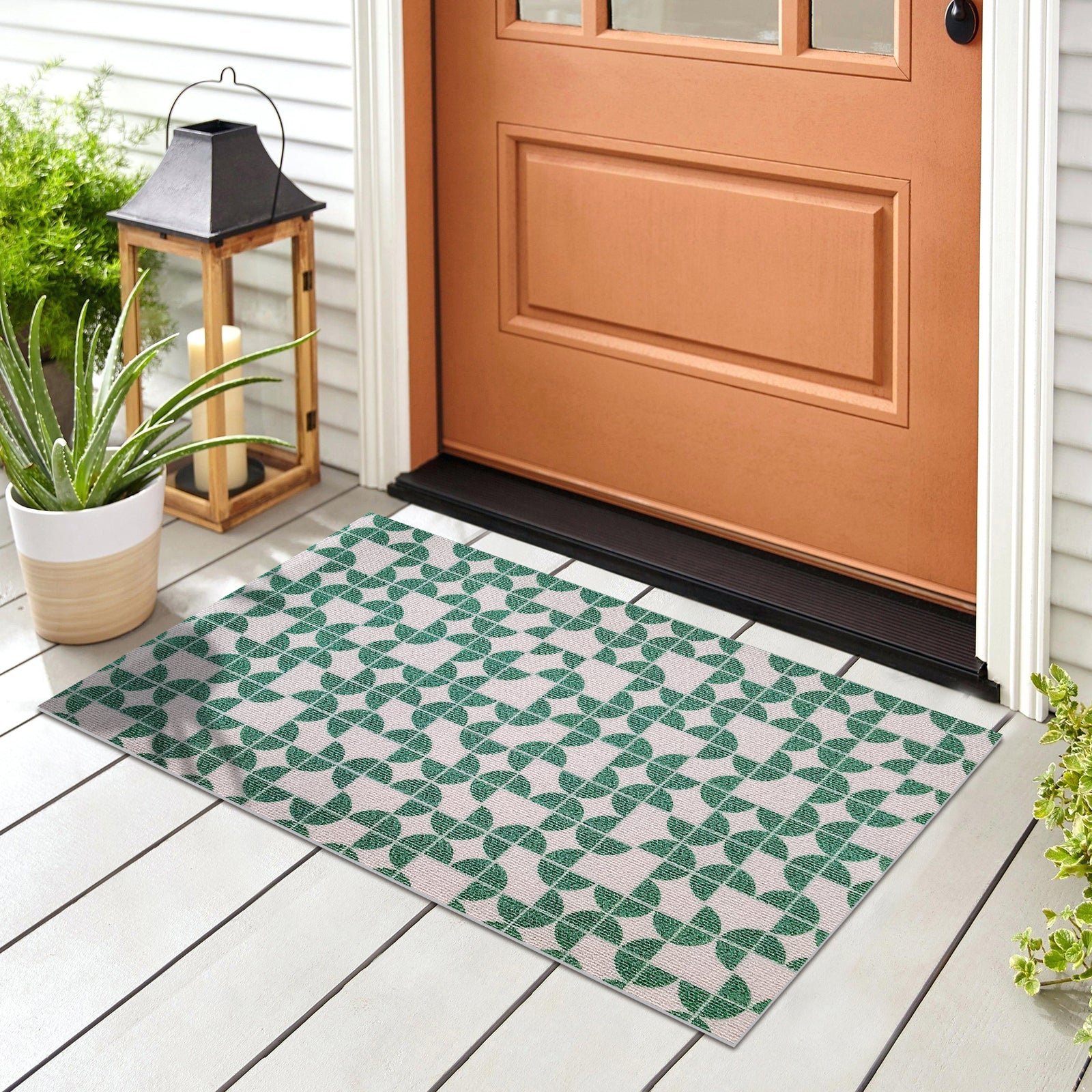 Angell 60x90cm Modern Outdoor Floor Doormat in Teal, featuring a geometric leaf pattern, placed on a painted porch floor, surrounded by a potted succulent and a wooden lantern with a candle.