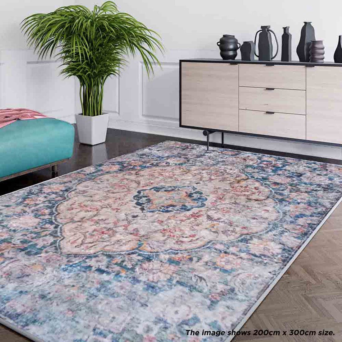 Ariza 120x170cm Small Persian Silky Indoor Floor Rug displayed in a living-room corner, showcasing its intricate floral pattern on a dark green base. It complements the teal bench and light-wood sideboard nearby.