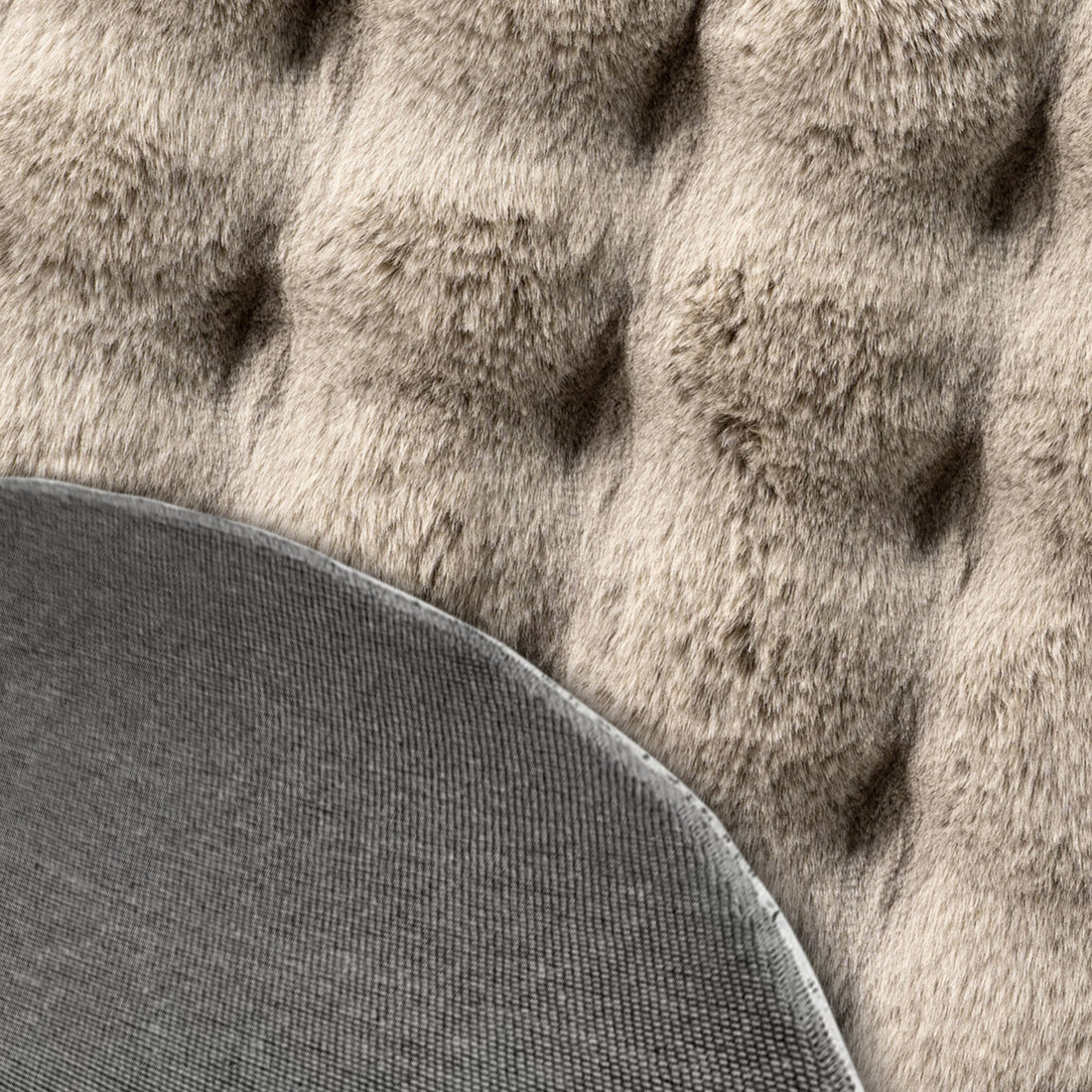 Close-up of Armida Beige Round Faux Fur Bubble Rug 160cm, showcasing plush tufted texture behind a tightly woven grey fabric, highlighting the rug's luxurious, soft faux fur design.