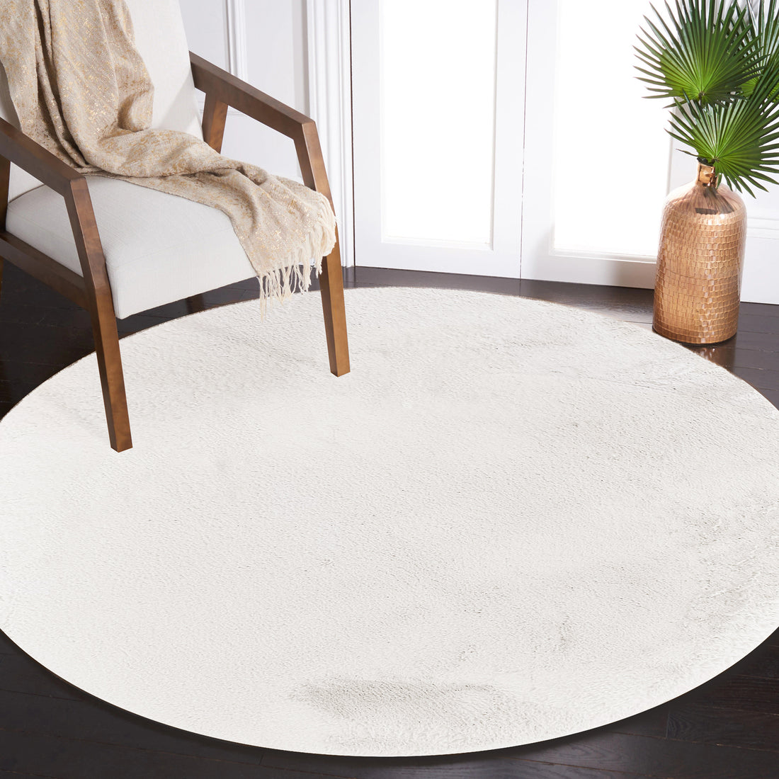 Azaliya 160x160cm Faux Rabbit Fur Floor Rug in Cream White on dark hardwood floor, enhancing a modern, minimalist room with a mid-century armchair, cream-and-gold throw, and copper vase with palm fronds.