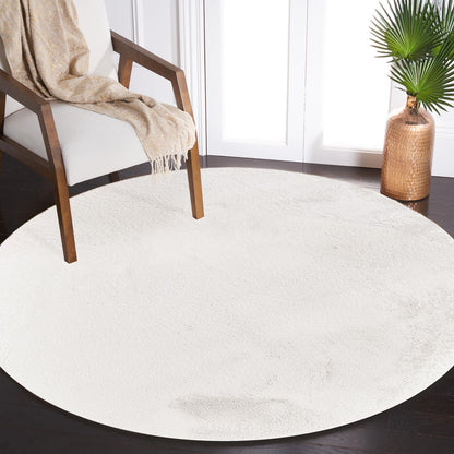 Azaliya 160x160cm Faux Rabbit Fur Floor Rug in Cream White on dark hardwood floor, enhancing a modern, minimalist room with a mid-century armchair, cream-and-gold throw, and copper vase with palm fronds.