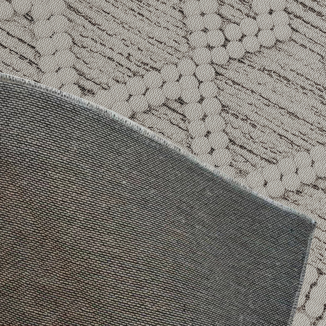 Benita 160x230cm Medium Soft Modern Printed Indoor Floor Rug close-up, showcasing its tight grey weave juxtaposed with a lighter, textured beige fabric with subtle black patterns.