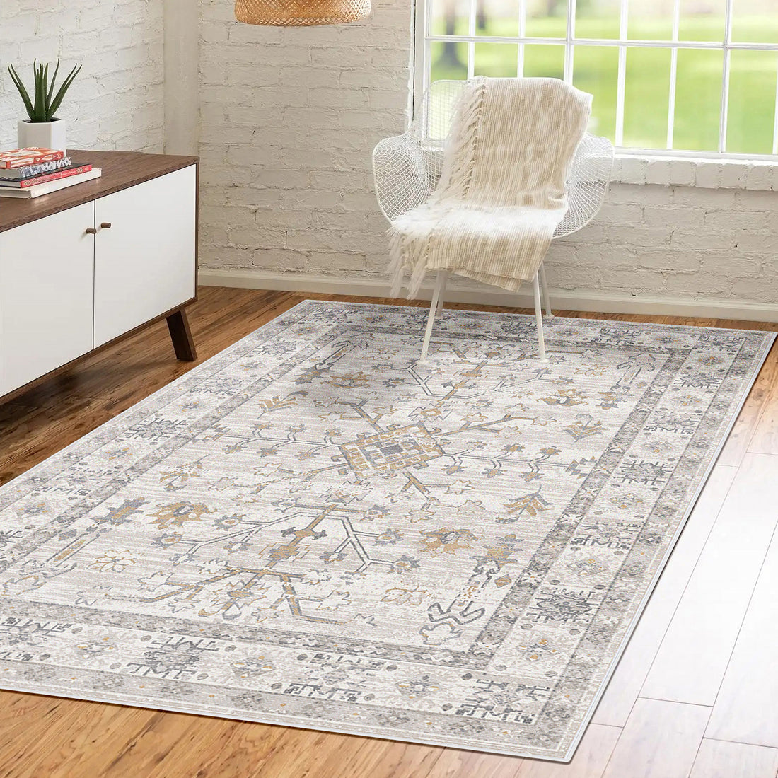 Bortan Persian Indoor Rug 120x180cm displayed in a modern living space, featuring a light-tone pattern on hardwood floor, complemented by a mid-century sideboard and a wire-frame chair with a throw.