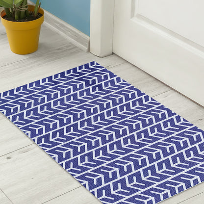 Carey 45x75cm Outdoor Doormat in White & Indigo, featuring a white geometric pattern on a purple rug in front of a closed white door, with a yellow plant pot nearby.